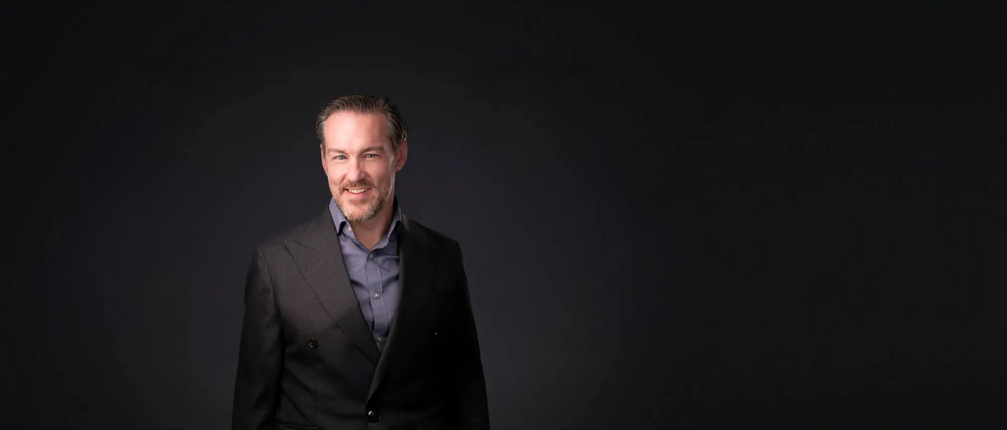 Shay Lynch in a dark suit jacket against a dark background